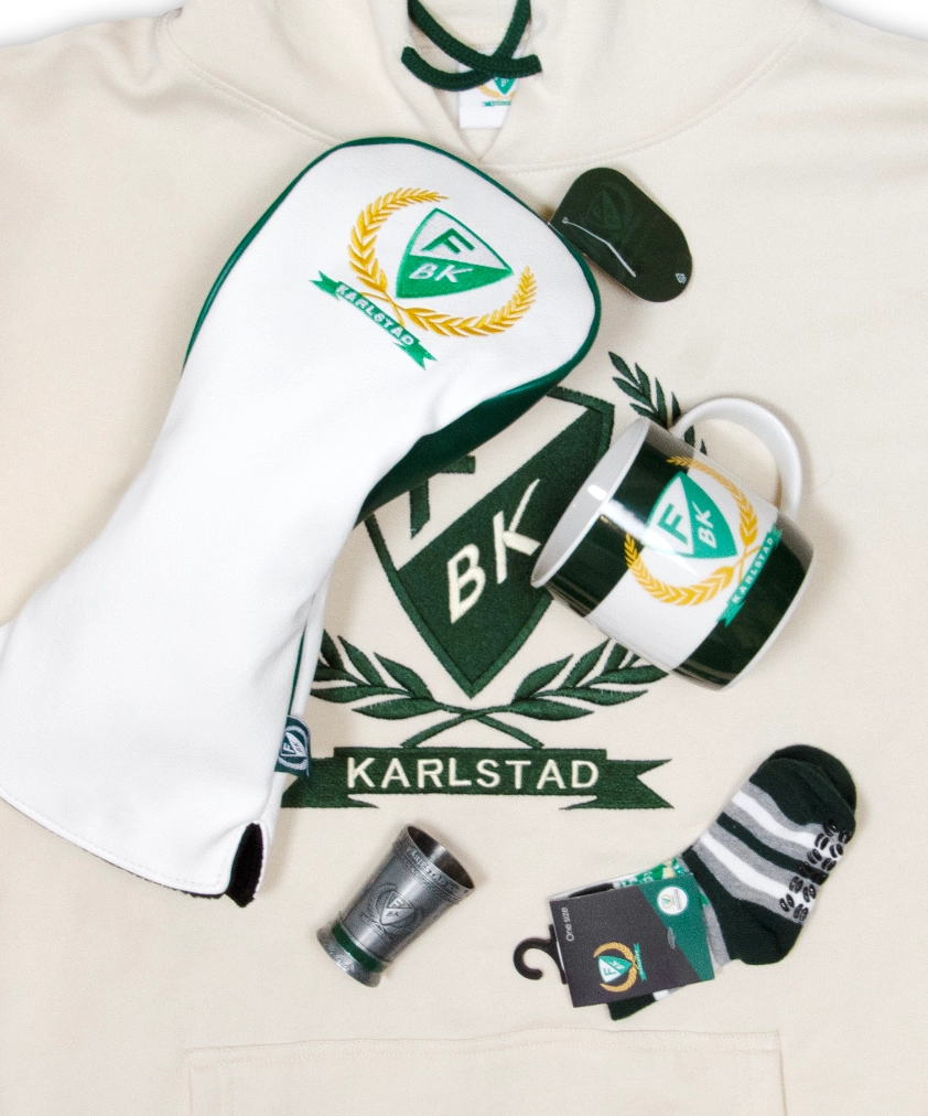 Färjestad BK merchandise utlagd på en gräddvit hoodie: ett vit- och grönfärgat golfklubbsfodral, en randig mugg, ett litet snapsglas i metall och ett par randiga strumpor